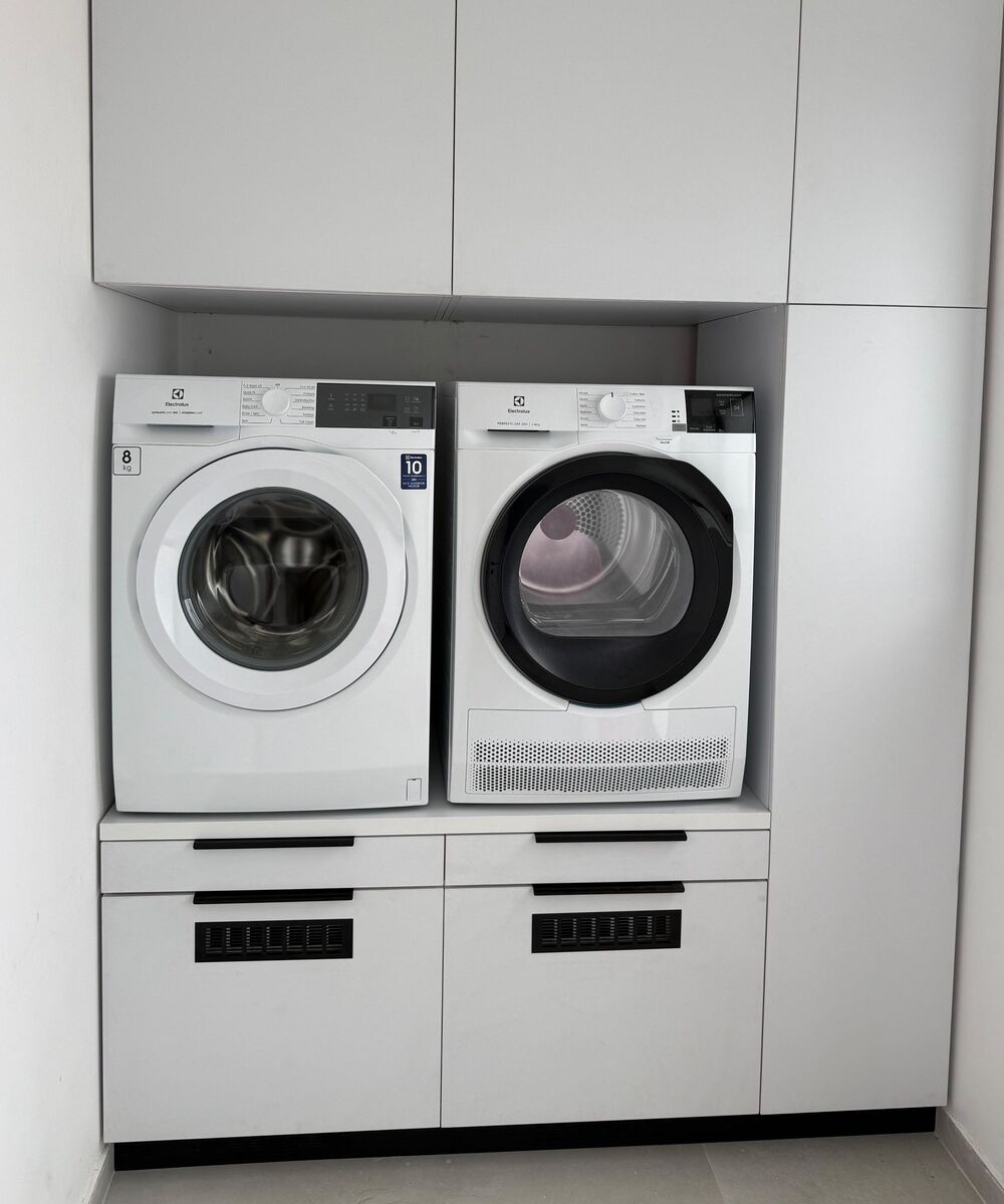 Example of a white front-load washer and dryer side by side on a raised platform with drawers