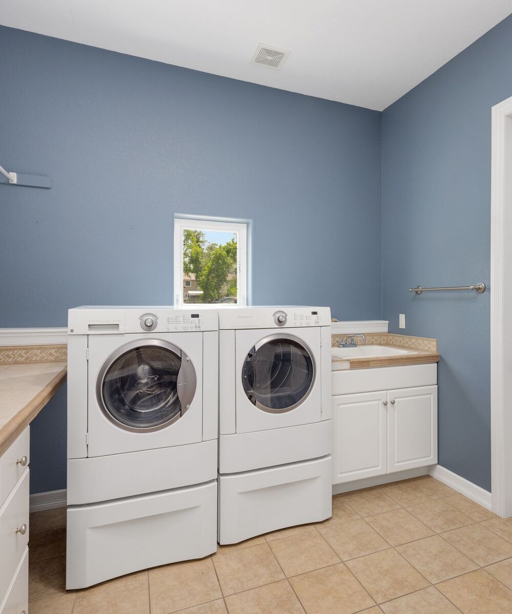 Example of a white front-load washer and dryer side by side on pedestals in a laundry room