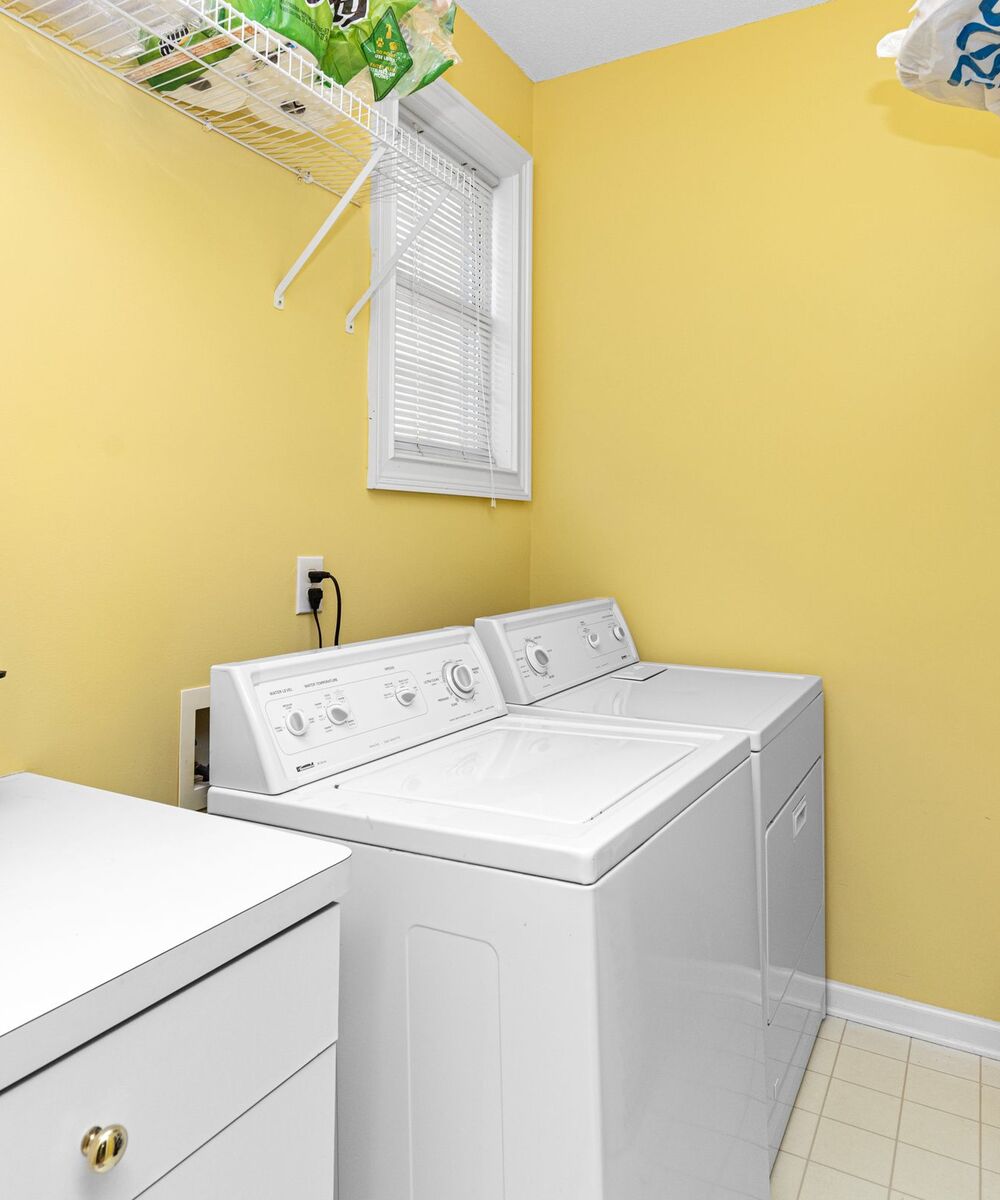 Example of a white top-load washer and matching dryer in a laundry room with yellow walls